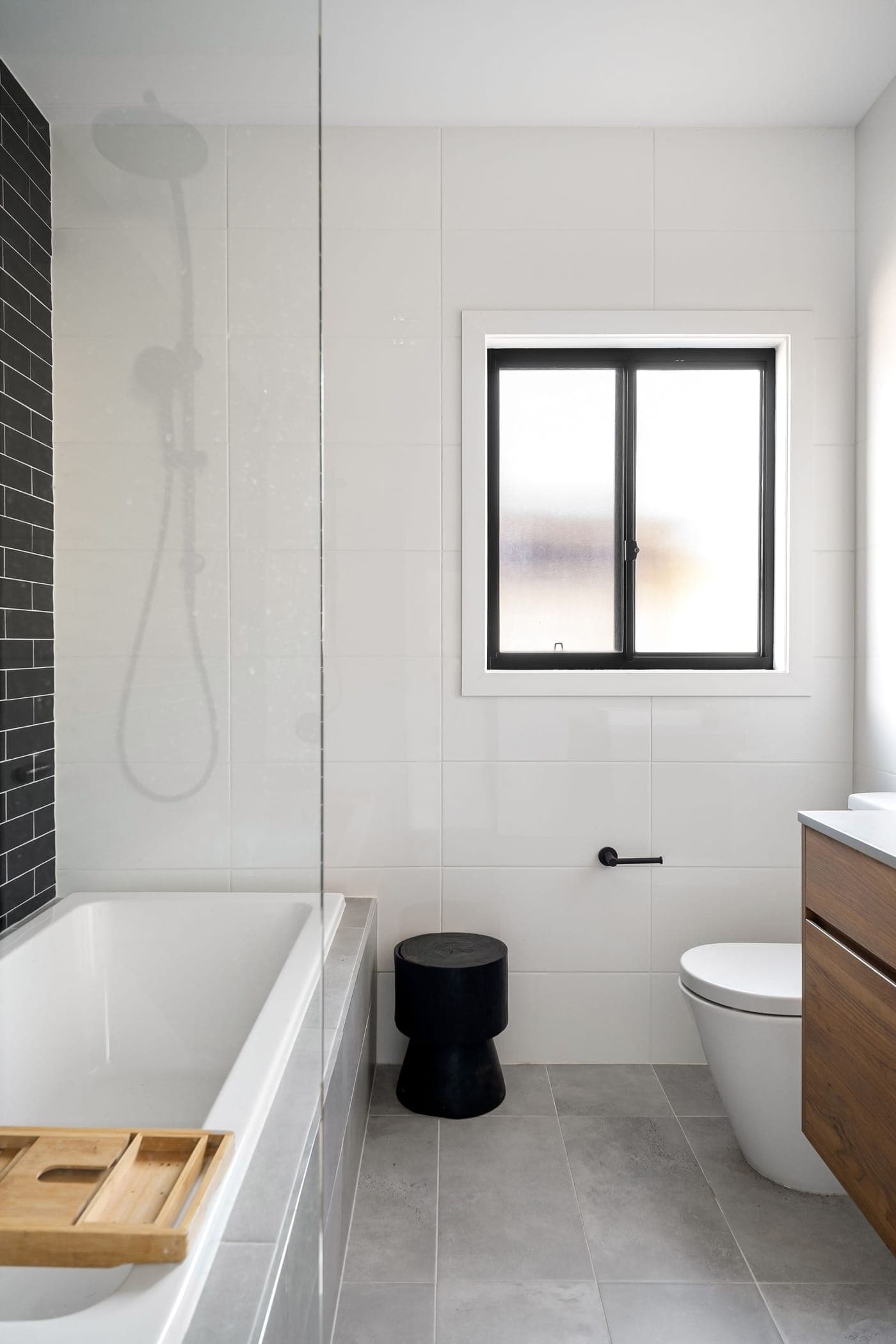 Lyst badeværelse med badekar, toilet og underskab i træ